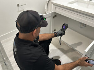 Signs of a water leak in your home: a home inspector uses a thermal imaging camera to check under a bathroom sink cabinet in a Florida home