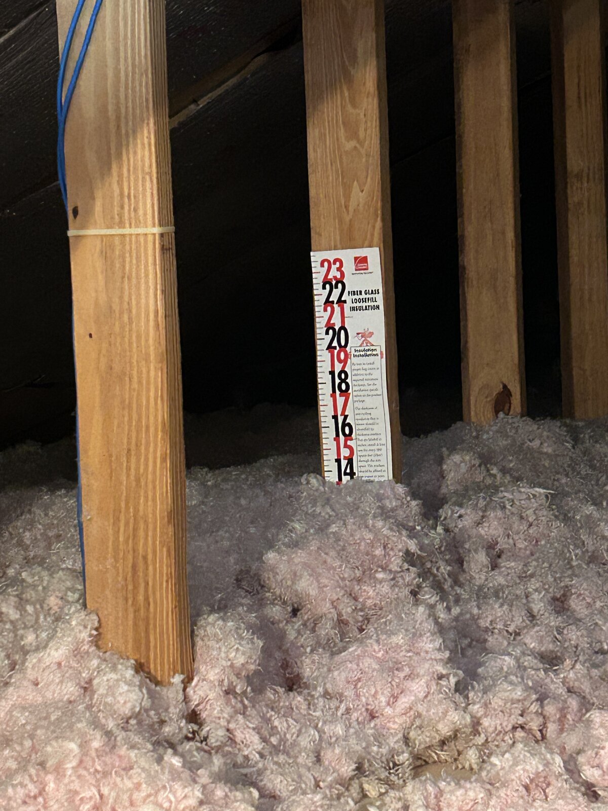 Attic insulation depth ruler photographed to document insulation level during a home inspection