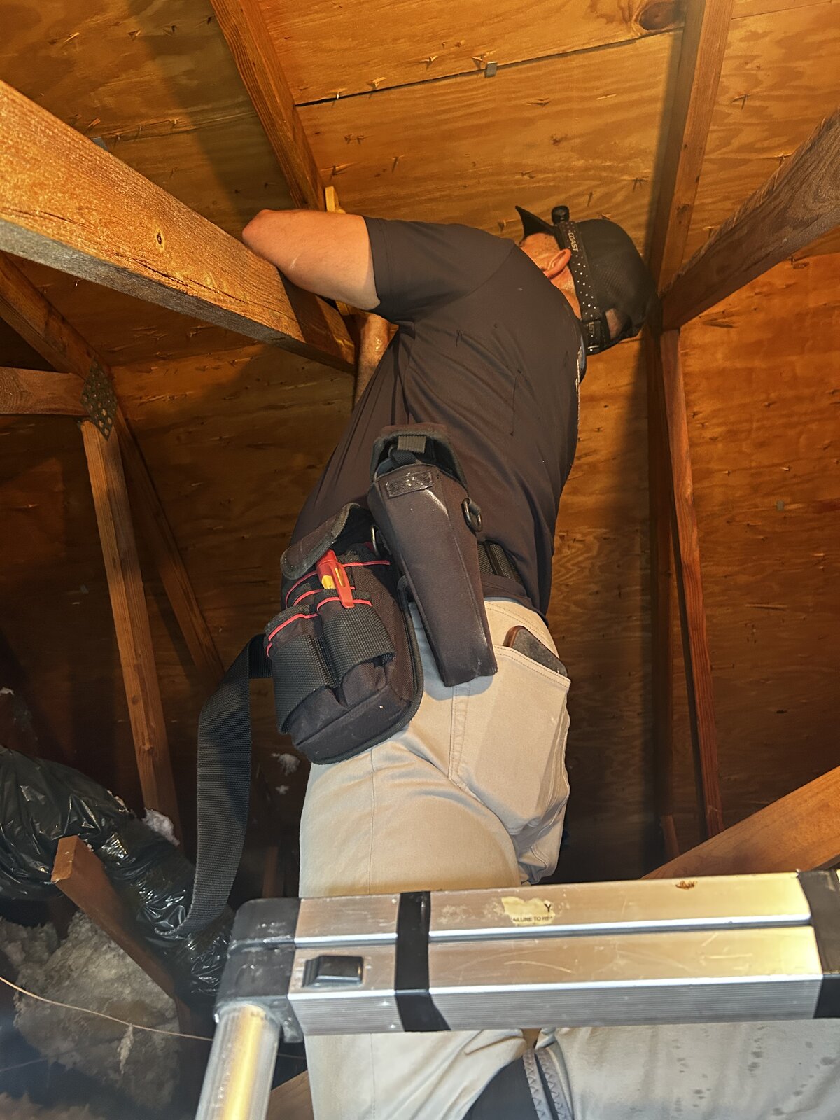 Home inspector examining roof framing and sheathing in an attic