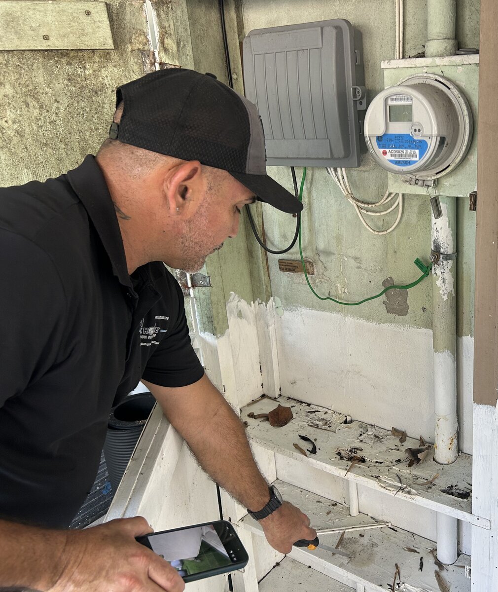 Home inspector documenting the exterior electrical meter and service equipment during a Florida home inspection
