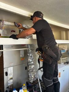 Home inspector checking an AC air handler and ductwork in a closet, part of evaluating AC humidity control in a Florida home